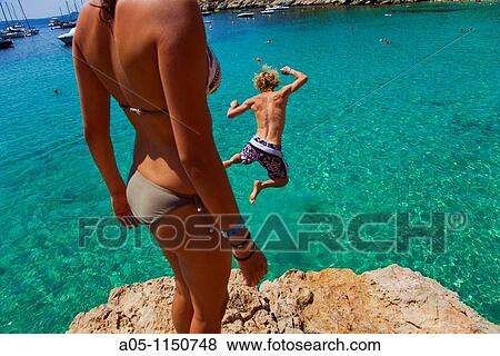 Young boy jumping into sea. Cala Salada beach. Santa Agn's de Corona. Ibiza. Balearic Islands. Spain. View Large Photo Image Stock Photo - Young boy jumping into sea. Cala Salada beach. Santa Agn's de Corona. Ibiza. Balearic Islands. Spain.. Fotosearch