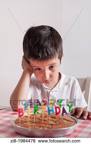 Stock Photo - Young boy looking at birthday cake.. Fotosearch
