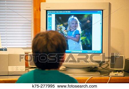 Young boy looking at photo on computer monitor View Large Photo Image Stock Photography - Young boy looking at photo on computer monitor. Fotosearch