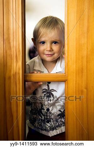 Stock Image - Young boy looking through window - Fort Lauderdale, Florida USA. Fotosearch