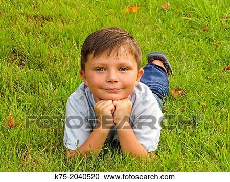 Young boy lying down on lawn View Large Photo Image Stock Image - Young boy lying down on lawn. Fotosearch