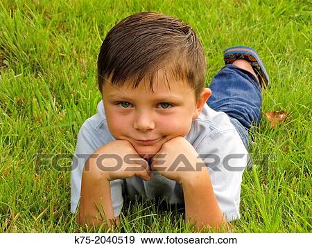 Young boy lying down on lawn View Large Photo Image Stock Photo - Young boy lying down on lawn. Fotosearch