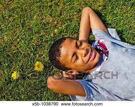 young boy lying on grass, below camera, african american, multiracial, vertical View Large Photo Image Stock Image - young boy lying on grass, below camera, african american, multiracial, vertical. Fotosearch