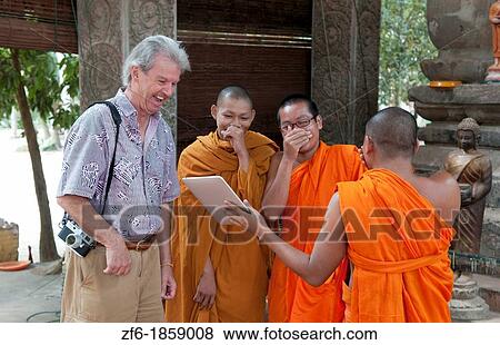 Young boy monks laughing and having fun at Apple Digital Tablet computer game with tourist man in Siem Reap in Cambodia Asia relaxing and being boys View Large Photo Image Stock Photo - Young boy monks laughing and having fun at Apple Digital Tablet computer game with tourist man in Siem Reap in Cambodia Asia relaxing and being boys. Fotosearch