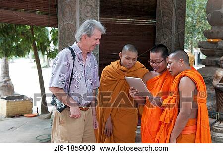 Young boy monks laughing and having fun at Apple Digital Tablet computer game with tourist man in Siem Reap in Cambodia Asia relaxing and being boys View Large Photo Image Stock Photo - Young boy monks laughing and having fun at Apple Digital Tablet computer game with tourist man in Siem Reap in Cambodia Asia relaxing and being boys. Fotosearch