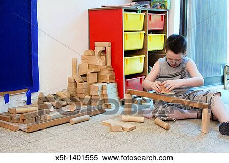 Young boy of 8 building with wooden building blocks in a playroom View Large Photo Image Stock Photography - Young boy of 8 building with wooden building blocks in a playroom. Fotosearch