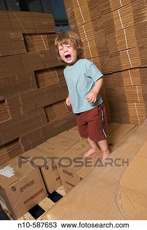 Young boy on a pile of cardboard boxes in a factory. View Large Photo Image Stock Image - Young boy on a pile of cardboard boxes in a factory.. Fotosearch