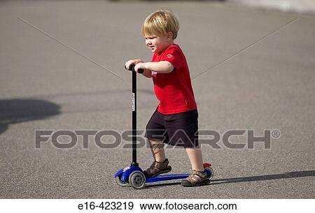 Young boy on scooter View Large Photo Image Stock Photo - Young boy on scooter. Fotosearch