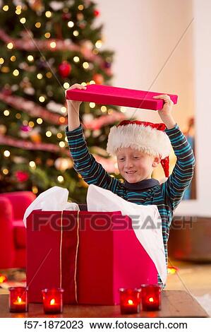 Young boy opening a Christmas present on Christmas day View Large Photo Image Stock Image - Young boy opening a Christmas present on Christmas day. Fotosearch