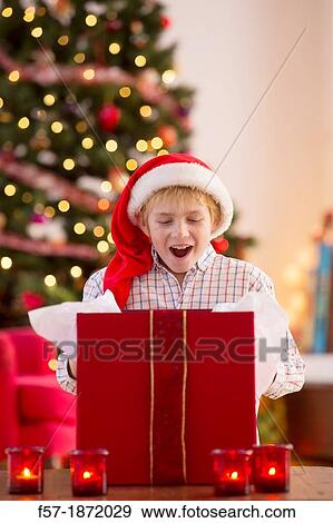 Young boy opening a Christmas present on Christmas day View Large Photo Image Stock Photo - Young boy opening a Christmas present on Christmas day. Fotosearch