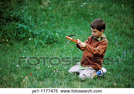 Young boy playing with a crossbow in a grassy field, Provence, France. View Large Photo Image Stock Photography - Young boy playing with a crossbow in a grassy field, Provence, France.. Fotosearch