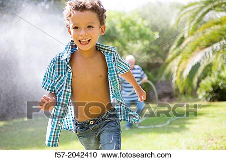 Stock Image - Young boy playing with his grandfather in the garden.. Fotosearch