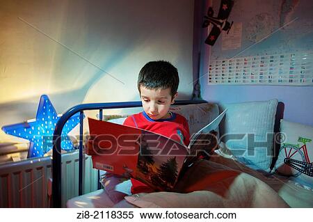 Stock Photography - Young boy, reading a bedtime story in his bed.. Fotosearch