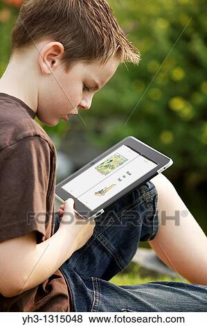 Young boy reading Winnie the Pooh story from an iPad in the garden View Large Photo Image Stock Photo - Young boy reading Winnie the Pooh story from an iPad in the garden. Fotosearch
