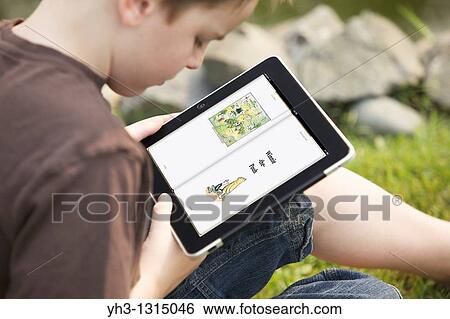 Young boy reading Winnie the Pooh story from an iPad in the garden View Large Photo Image Stock Photograph - Young boy reading Winnie the Pooh story from an iPad in the garden. Fotosearch