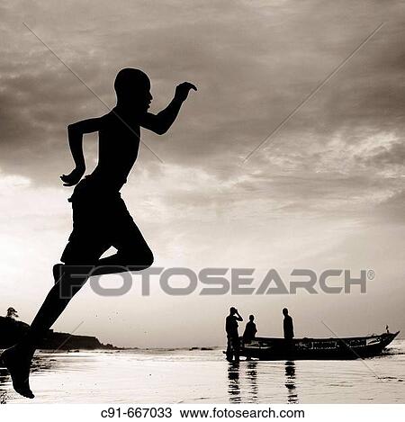 Young boy running on beach and fishermen in background. Gambia View Large Photo Image Stock Image - Young boy running on beach and fishermen in background. Gambia. Fotosearch