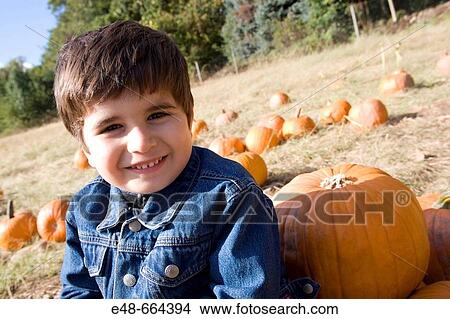 Young boy sitting by pumpkin in pumpkin patch View Large Photo Image Picture - Young boy sitting by pumpkin in pumpkin patch. Fotosearch