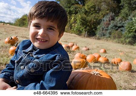 Young boy sitting by pumpkin in pumpkin patch View Large Photo Image Stock Photography - Young boy sitting by pumpkin in pumpkin patch. Fotosearch