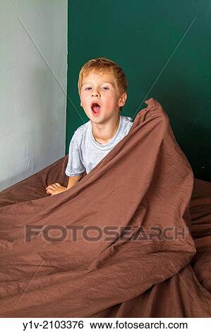Stock Photograph - Young boy sitting on his bed.. Fotosearch