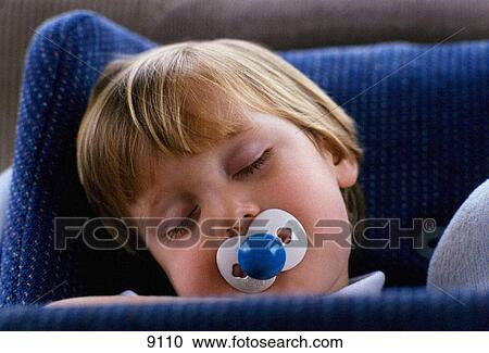 Stock Image - Young boy sleeping with his pacifier. Fotosearch