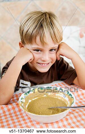 Stock Photo - Young boy smiling at camera while he is eating. Fotosearch