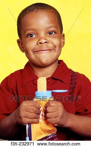 Stock Image - Young boy squeezing tube of yellow play material. Fotosearch