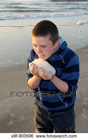 Young boy tasting sea foam at sunrise on Hunting Island in South Carolina, USA Hunting Island is well known for its five mile white sand beach and Atlantic Ocean sunrises View Large Photo Image Stock Photograph - Young boy tasting sea foam at sunrise on Hunting Island in South Carolina, USA Hunting Island is well known for its five mile white sand beach and Atlantic Ocean sunrises. Fotosearch