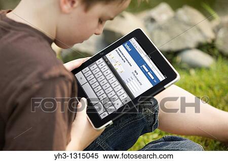 Young boy using an iPad to check his Facebook account View Large Photo Image Stock Photography - Young boy using an iPad to check his Facebook account. Fotosearch