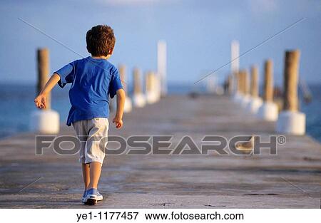 Young boy walking on a wooden jetty at sunset in Cancn, Quintana Roo, YucatBn Peninsula, Mexico. View Large Photo Image Stock Photo - Young boy walking on a wooden jetty at sunset in Cancn, Quintana Roo, YucatBn Peninsula, Mexico.. Fotosearch