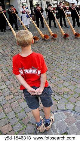 Stock Photo - young boy watching adult swiss people playing with alpine horns, on the street of town Vevey, Switzerland. Fotosearch