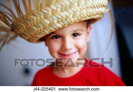 Stock Image - Young boy wearing a straw hat and smiling. Fotosearch