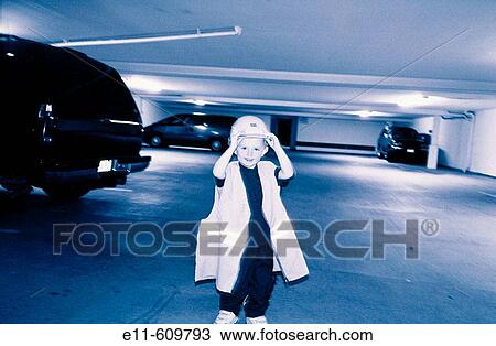 Stock Image - Young boy wearing adult safety hat and vest. Fotosearch