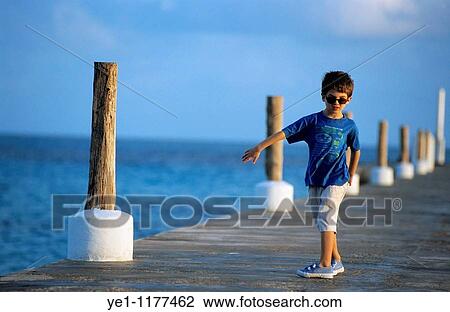 Young boy wearing sunglasses on a wooden jetty at sunrise. View Large Photo Image Stock Image - Young boy wearing sunglasses on a wooden jetty at sunrise.. Fotosearch