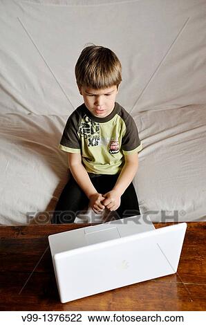 Stock Image - young boy who watches a movie on the computer. Fotosearch