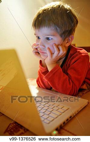 young boy who watches a movie on the computer View Large Photo Image Stock Photograph - young boy who watches a movie on the computer. Fotosearch