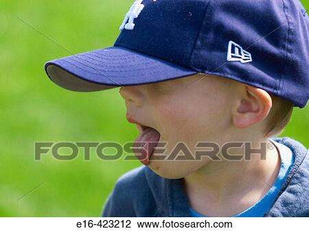 Young boy with baseball cap licking face. View Large Photo Image Stock Image - Young boy with baseball cap licking face.. Fotosearch