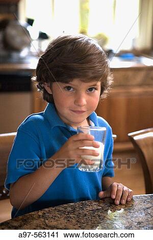 Young boy with blue shirt holding a glass of milk. View Large Photo Image Stock Image - Young boy with blue shirt holding a glass of milk.. Fotosearch
