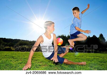 Stock Photograph - Young boys playing soccer on a meadow, Germany.. Fotosearch
