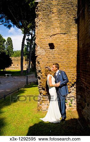 Young bride and groom kissing near stone wall View Large Photo Image Stock Photography - Young bride and groom kissing near stone wall. Fotosearch
