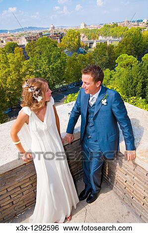 Stock Photograph - Young bride and groom standing on terrace in Rome, Italy. Fotosearch