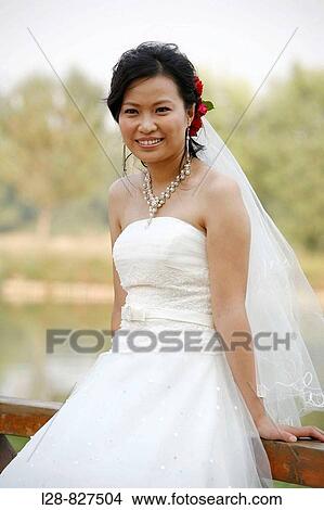 Young bride standing in park, portrait View Large Photo Image Picture - Young bride standing in park, portrait. Fotosearch