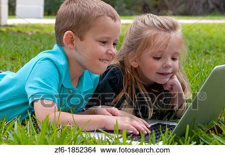 Young brother and sister aged only 5 and 3 playing in front yard with computer and internet games really getting along and interested View Large Photo Image Picture - Young brother and sister aged only 5 and 3 playing in front yard with computer and internet games really getting along and interested. Fotosearch