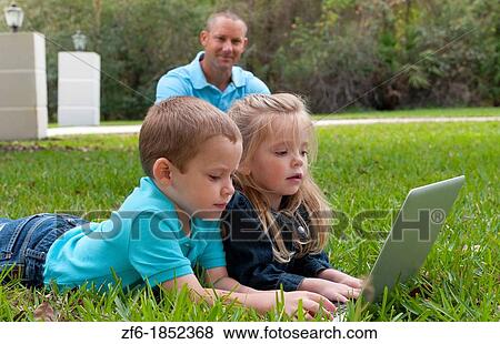 Young brother and sister aged only 5 and 3 playing in front yard with computer and internet games really getting along and interested while father sits in the background happy and proud View Large Photo Image Stock Photo - Young brother and sister aged only 5 and 3 playing in front yard with computer and internet games really getting along and interested while father sits in the background happy and proud. Fotosearch