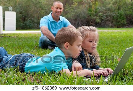 Young brother and sister aged only 5 and 3 playing in front yard with computer and internet games really getting along and interested while father sits in the background happy and proud View Large Photo Image Stock Photo - Young brother and sister aged only 5 and 3 playing in front yard with computer and internet games really getting along and interested while father sits in the background happy and proud. Fotosearch