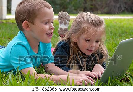 Young brother and sister aged only 5 and 3 playing in front yard with computer and internet games really getting along and interested View Large Photo Image Stock Photography - Young brother and sister aged only 5 and 3 playing in front yard with computer and internet games really getting along and interested. Fotosearch