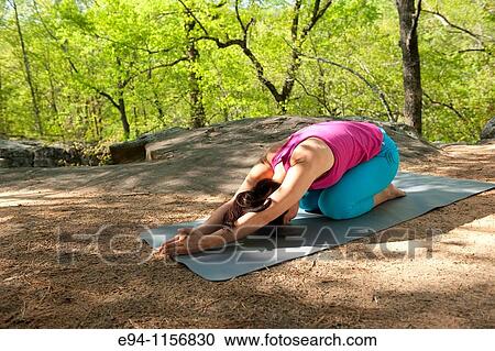 Stock Image - Young brunette woman doing yoga poses in a forest setting in the springtime.. Fotosearch