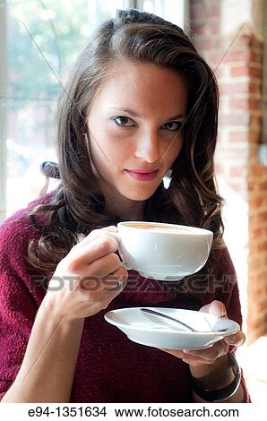 Young brunette woman holding a large white coffee cup looking directly at the camera View Large Photo Image Picture - Young brunette woman holding a large white coffee cup looking directly at the camera. Fotosearch