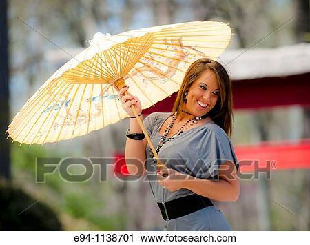 Young brunette woman in a mini-skirt in a garden setting holding a parasol looking away from the camera. View Large Photo Image Stock Image - Young brunette woman in a mini-skirt in a garden setting holding a parasol looking away from the camera.. Fotosearch