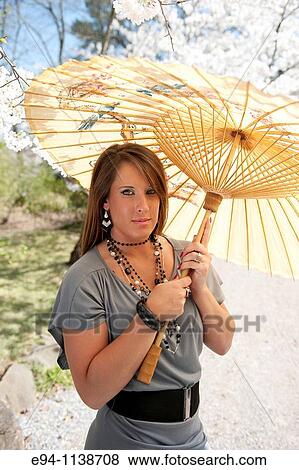 Young brunette woman in a mini-skirt in a garden setting holding a parasol looking at the camera. View Large Photo Image Stock Photo - Young brunette woman in a mini-skirt in a garden setting holding a parasol looking at the camera.. Fotosearch