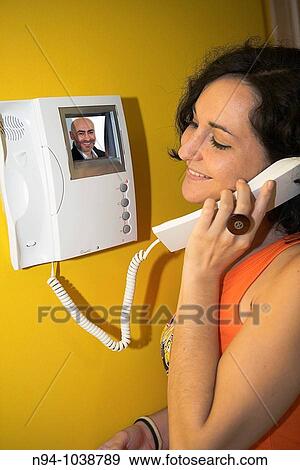 Stock Photo - Young brunette woman, speaking by video entry.. Fotosearch